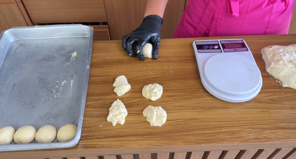 Bolinhas de massa sendo boleadas e dispostas na forma